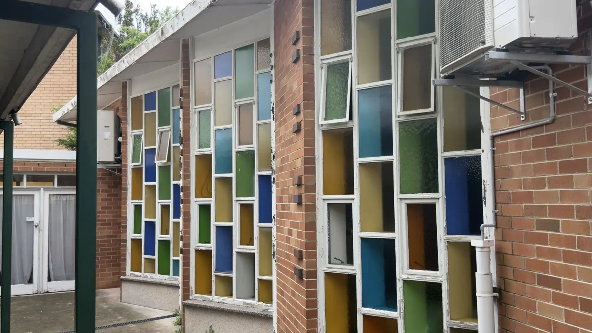 Coloured glass windows along the brick wall of Liverpool Uniting Church